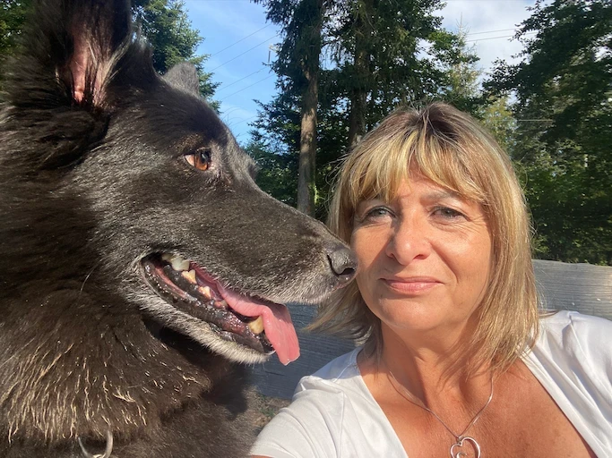 Pet-sitter en extérieur, joue contre joue avec un grand chien noir